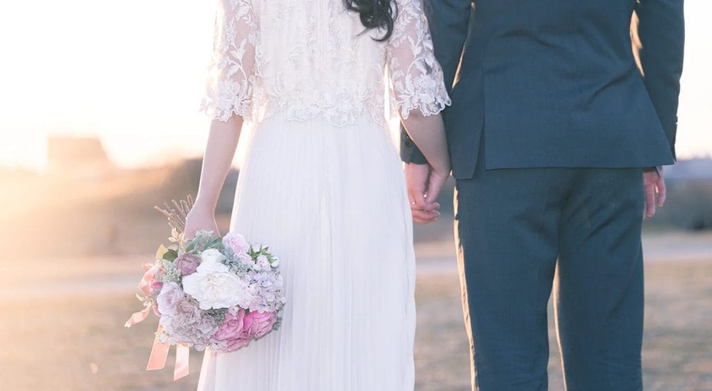 光り輝く未来へ向かって手をつなぎ歩き出す新郎新婦の後ろ姿