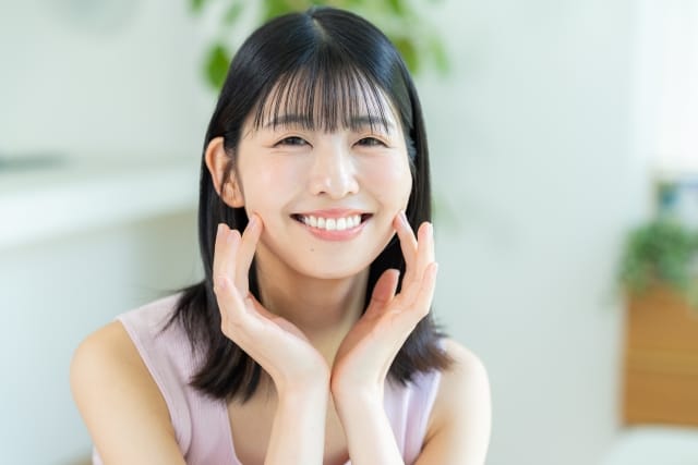 鏡を前にしてスキンケアを行い、明るく透明感のある肌を喜ぶ30代の日本人女性