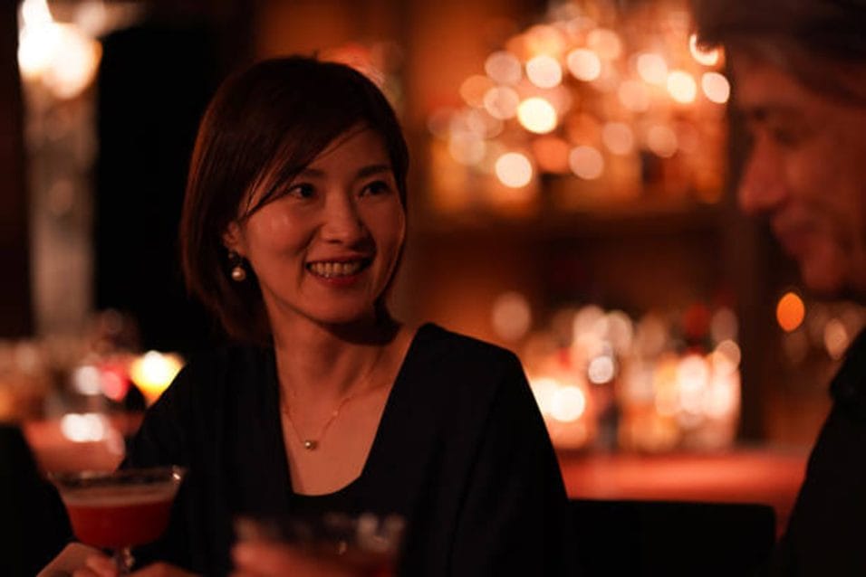 落ち着いた照明のレストランで、リラックスして向き合い会話を楽しむカップル