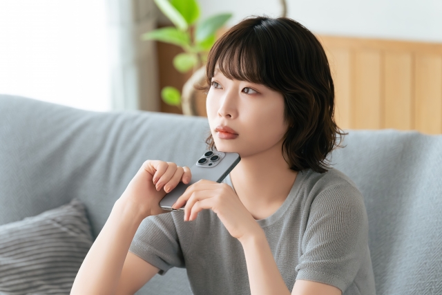 窓際で物思いにふける30代女性の横顔。婚活の悩みや迷走を表現したイメージ画像。