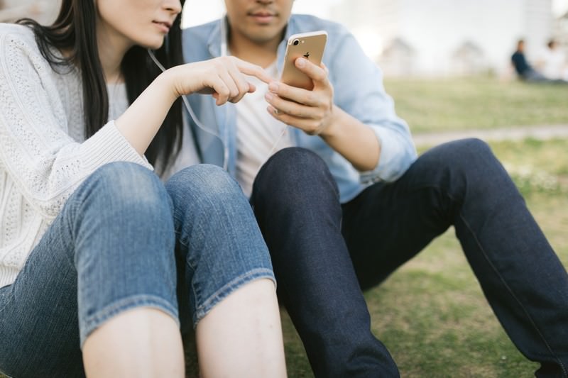 好きな曲をイヤホンで共有する恋人たちのスマートフォン音楽鑑賞